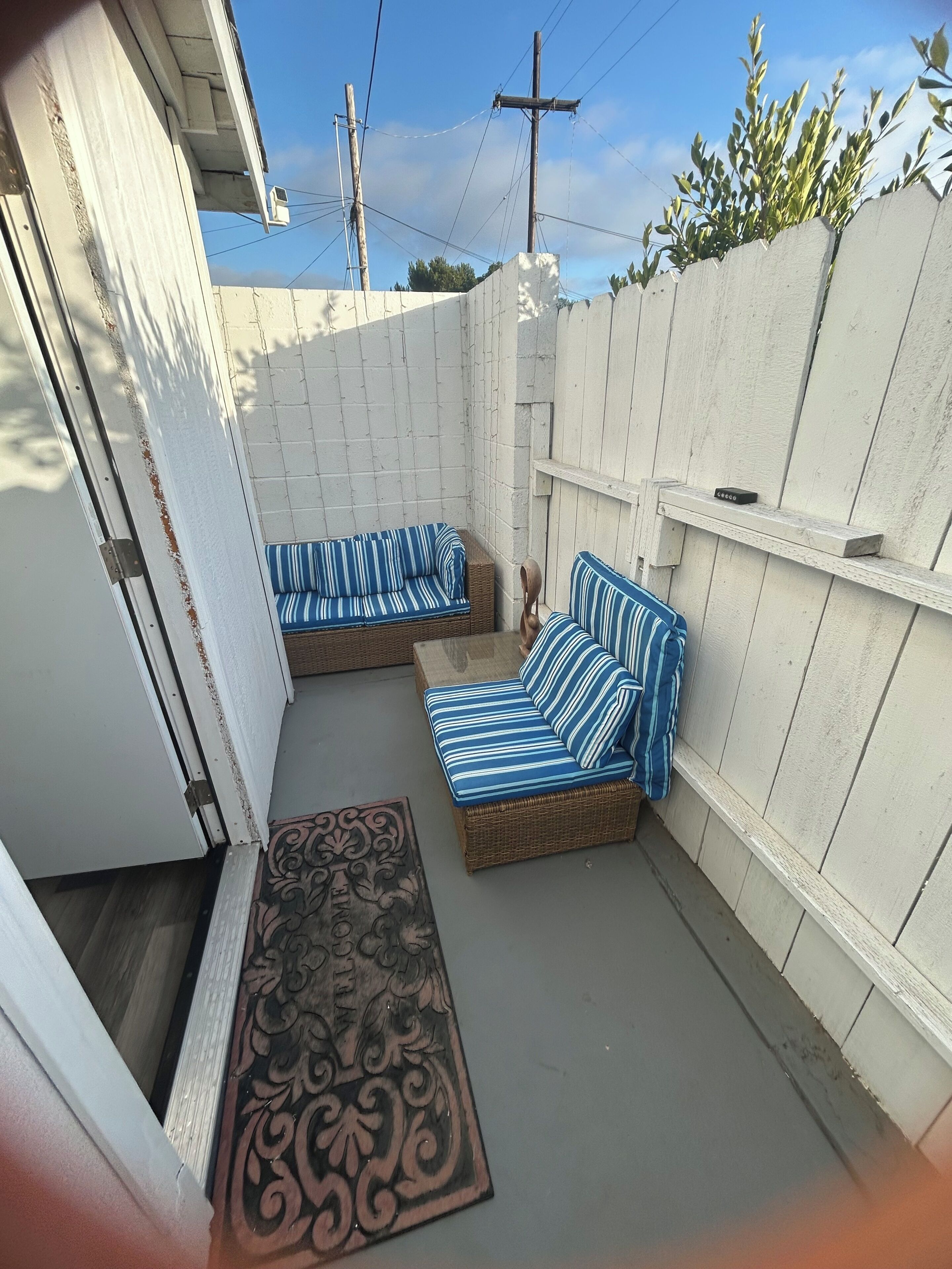 A covered outdoor seating area with two wicker sofas and a decorative rug.