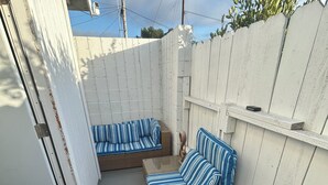 A covered outdoor seating area with two wicker sofas and a decorative rug.