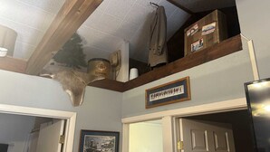 Ein Zimmer mit Deckenventilator, einem aufgehängten Hirschkopf, einem gerahmten Bild und einer Tür.