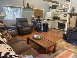 Een woonkamer met een bruine leren bank, een houten salontafel en een decoratief plaid.
