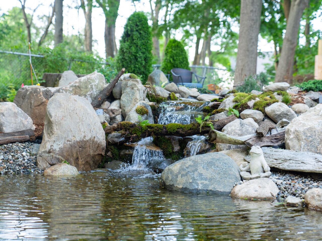 A serene pond with rocks and a small waterfall.