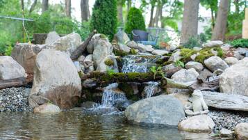 A serene pond with rocks and a small waterfall.