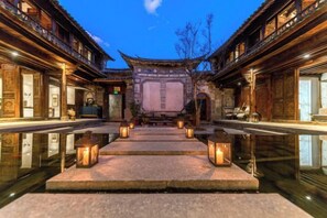 Un patio tradicional con un estanque reflectante en el centro, escalones de piedra y faroles.
