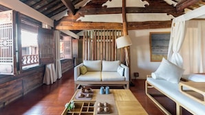 A traditional wooden interior with a sofa, a table with teapots, and a hanging lamp. - Manyue Wangjiayuan Hostel (Dali City)