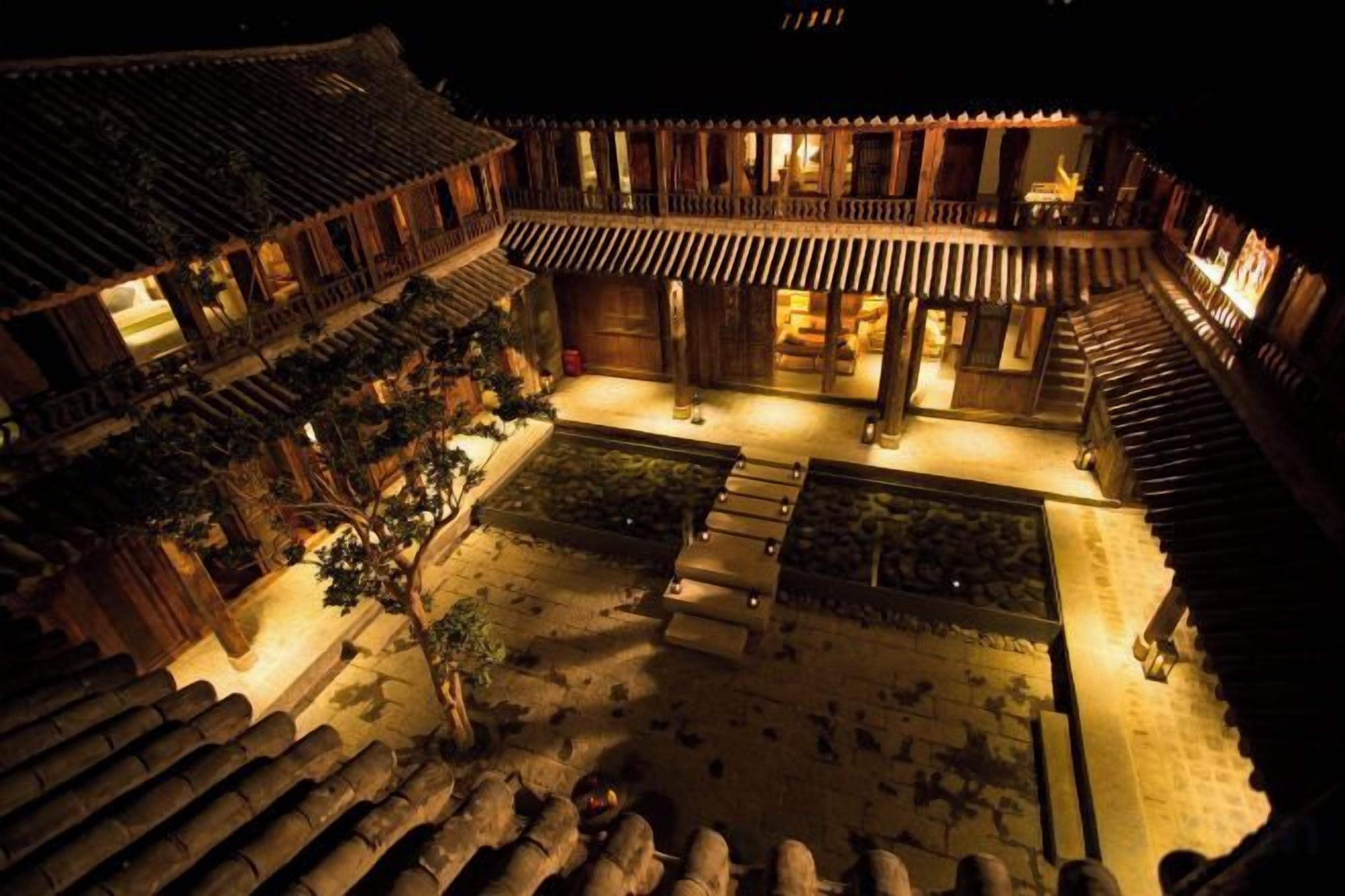 A traditional courtyard with wooden structures, a central open space, and steps leading to the entrance.