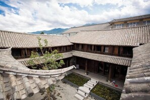 A traditional courtyard with tiled roofs and wooden structures, surrounded by mountains. - Manyue Wangjiayuan Hostel (Dali City)