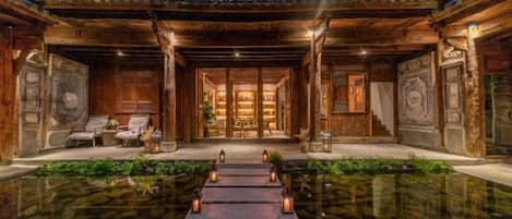 A traditional wooden building with a central courtyard, a reception area, and a view of the interior.