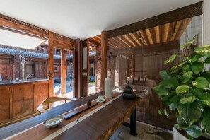 A traditional wooden interior with a long table, a potted plant, and a view of a traditional building outside. - Manyue Wangjiayuan Hostel (Dali City)