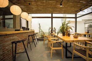 A restaurant with a brick wall, wooden tables, and chairs, and large windows. - Manyue Wangjiayuan Hostel (Dali City)