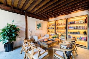 A cozy room with a wooden ceiling, a large bookshelf, and a seating area with chairs and a table. - Manyue Wangjiayuan Hostel (Dali City)
