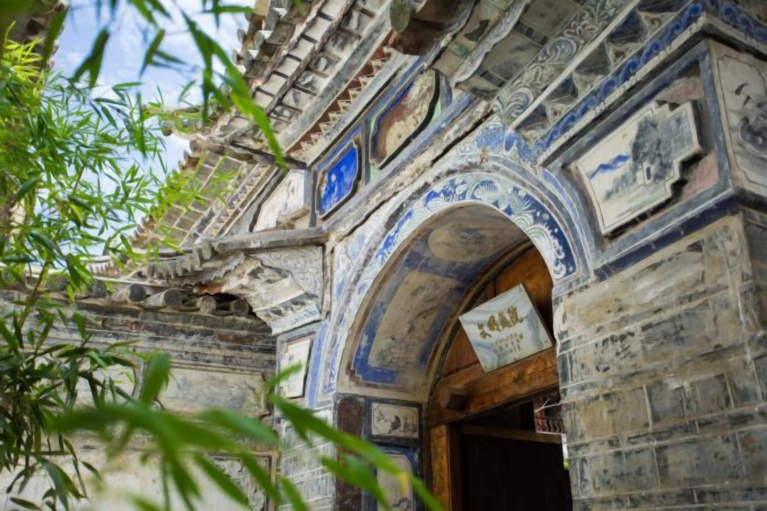 An arched entrance with intricate carvings and a signboard.