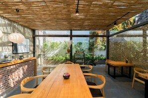 A modern interior with a long wooden table, seating, and a brick accent wall. - Manyue Wangjiayuan Hostel (Dali City)
