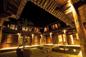 A traditional courtyard with wooden architecture, a central water feature, and illuminated by ambient lighting. - Manyue Wangjiayuan Hostel (Dali City)