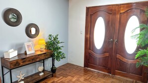 Piso de madeira em padrão herringbone, um console de madeira com uma luminária, obras de arte emolduradas e um vaso com planta.