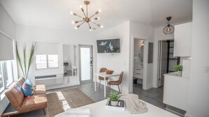 A modern living room with a sofa, a dining area, and a kitchen. - Agave on the Beach (Miami Beach)