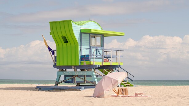 A lifeguard tower with a blue and green color scheme, located on a sandy beach with the ocean in the background. - Agave on the Beach (Miami Beach)