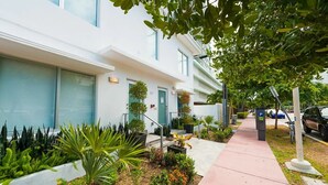 A modern building with a clean facade, a visible entrance, and a well-maintained garden area with various plants and flowers. - Agave on the Beach (Miami Beach)