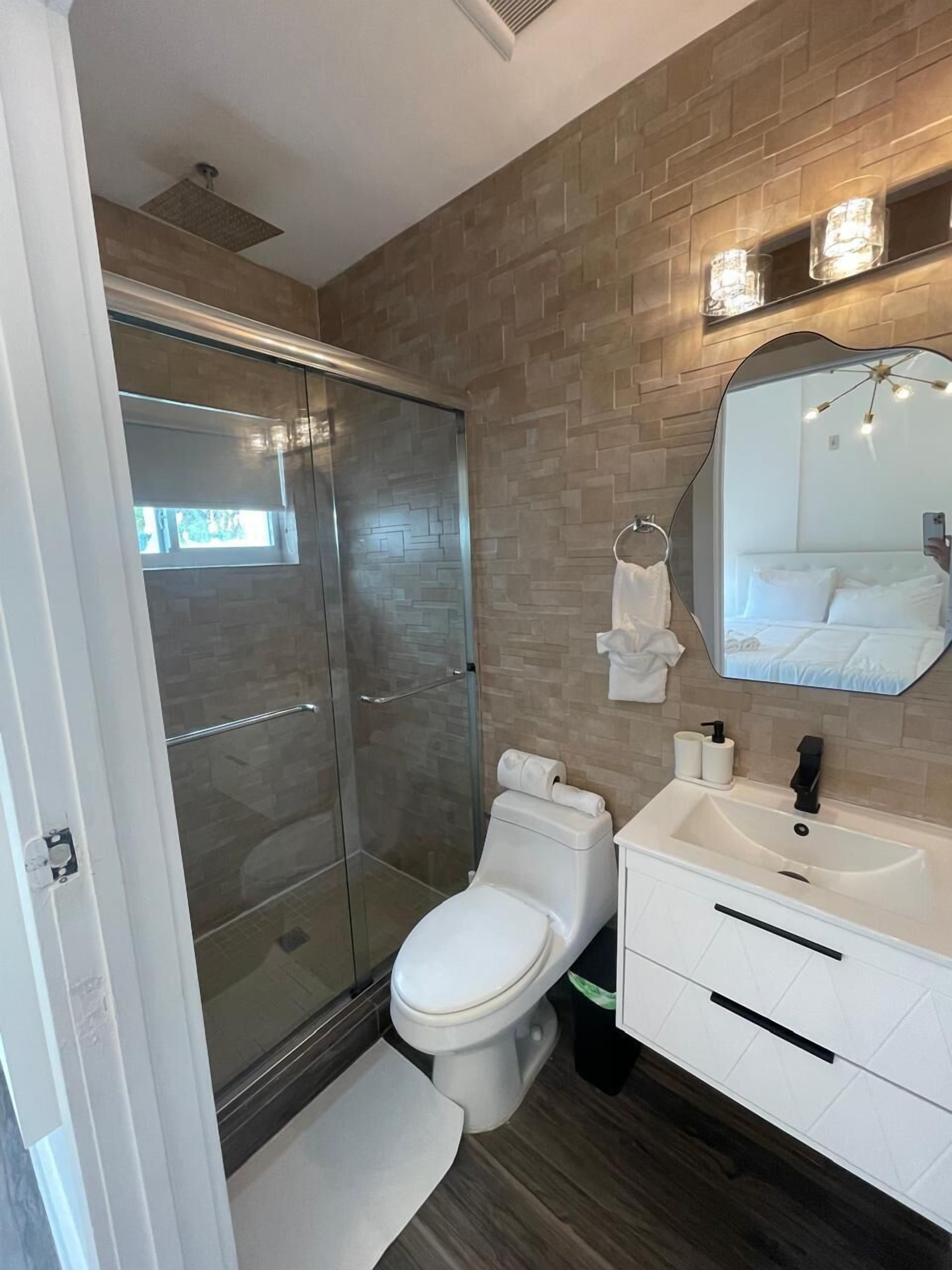 A modern bathroom with a glass shower enclosure, a white toilet, and a vanity with a mirror.