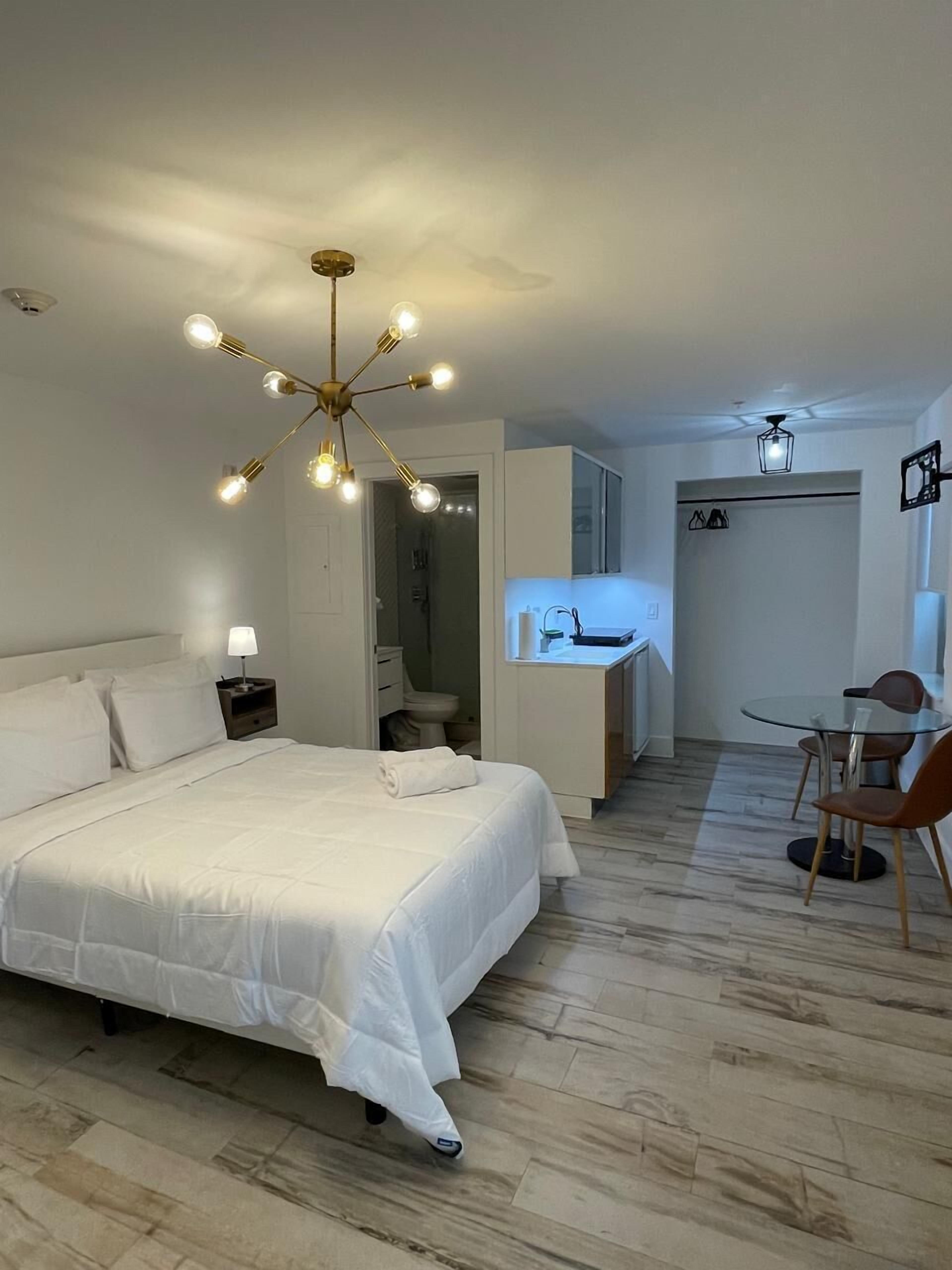 A modern hotel room with a large bed, a desk, and a dining area.