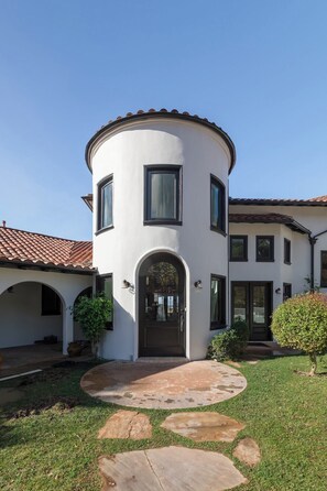 A two-story house with a circular design, a front door with a decorative glass panel, and a tiled roof.
