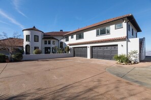 A two-story house with a garage, a driveway, and a small garden area. - Malibu Sky View Estate (Malibu)