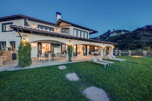 A modern two-story house with a patio, outdoor seating, and a well-maintained lawn. - Malibu Sky View Estate (Malibu)