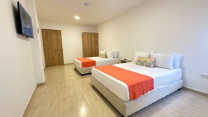 A hotel room with two beds, a wooden wardrobe, and a television on the wall. - Hotel Taybo Kai By St Hoteles (Santa Marta)