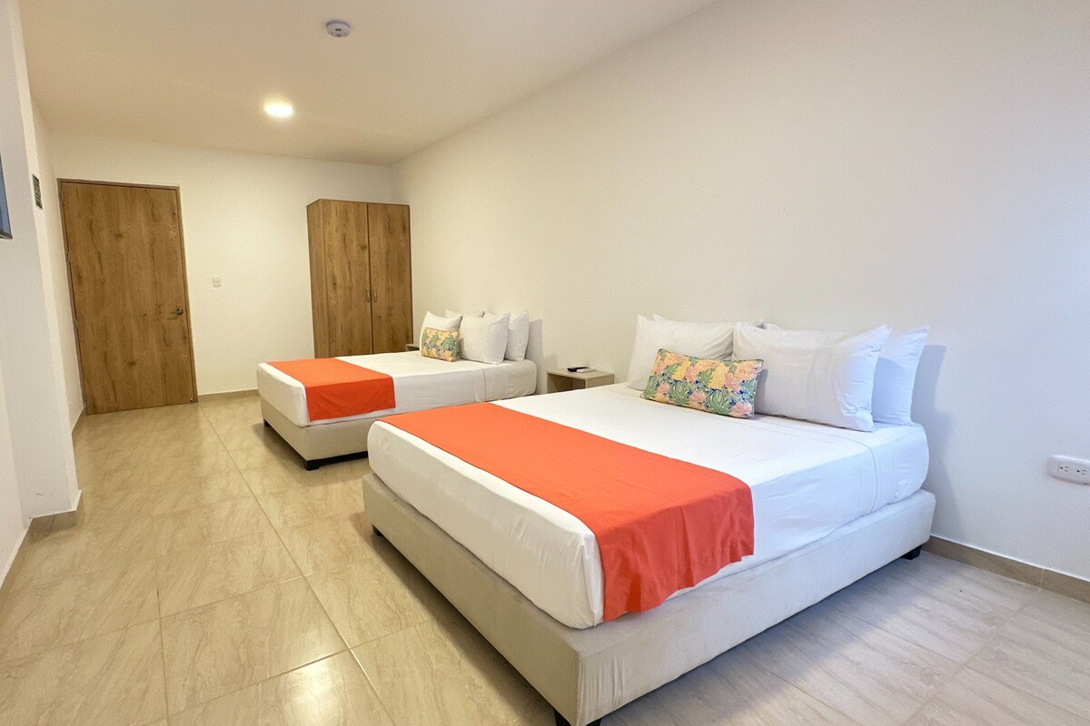 A hotel room with two beds, a wooden wardrobe, and a television on the wall.