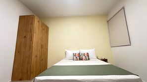 Un dormitorio con cama, armario de madera, mesita de noche y ventana con persianas.