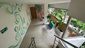 A hallway with a green spiral wall design, a staircase, and potted plants near a window. - Hotel Taybo Kai By St Hoteles (Santa Marta)