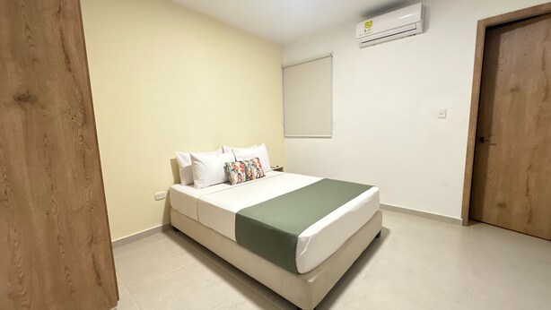 A bedroom with a bed, a wooden door, a white wall, and a white ceiling. - Hotel Taybo Kai By St Hoteles (Santa Marta)
