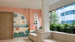 A modern lobby with a mural of a beach scene, a wooden door labeled "315", and a seating area with plants. - Hotel Taybo Kai By St Hoteles (Santa Marta)