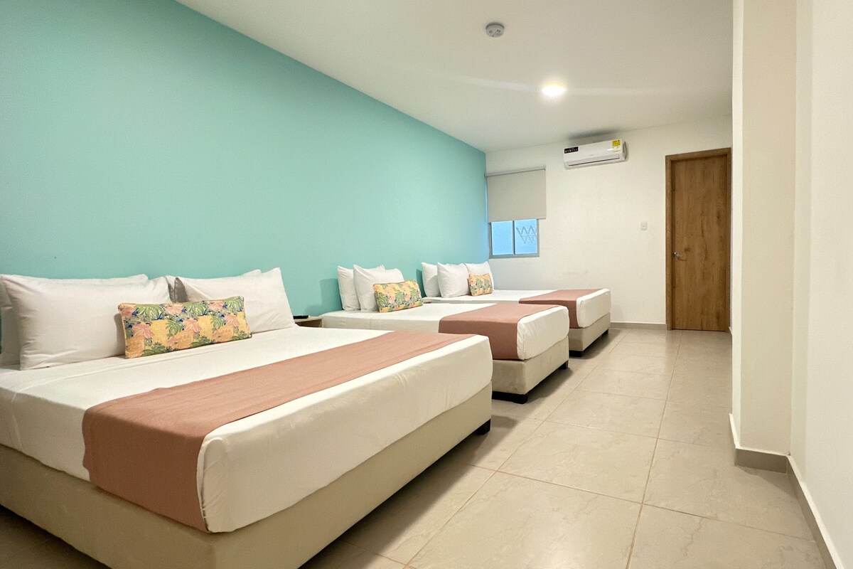 A hotel room with three beds, a teal wall, and a sign indicating 'NO MOLESTAR'.