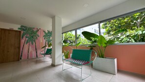 A room with a large window, a green chair, a wall with a tropical mural, and a potted plant. - Hotel Taybo Kai By St Hoteles (Santa Marta)