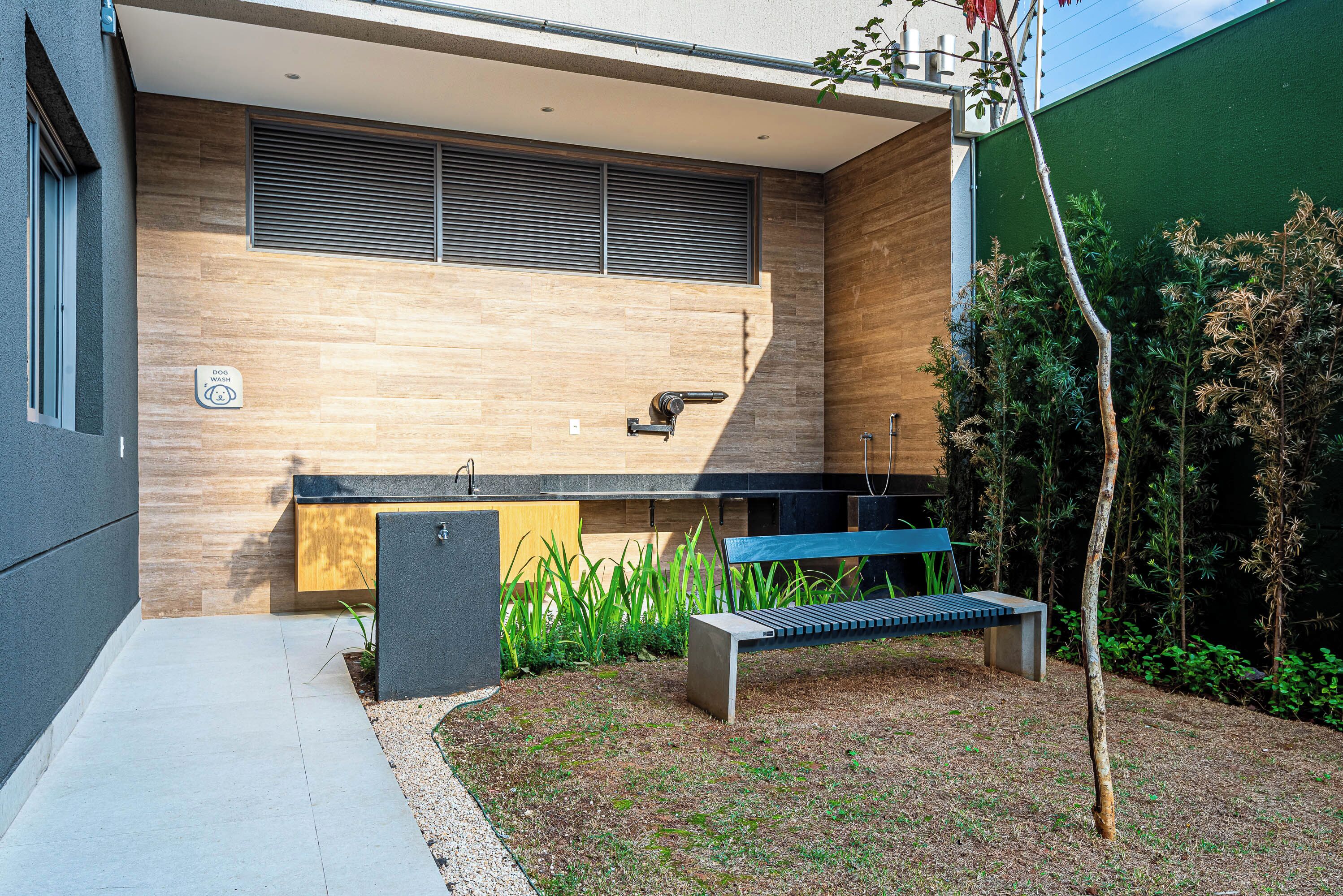 A modern outdoor kitchen area with a built-in sink, a bench, and a small tree.