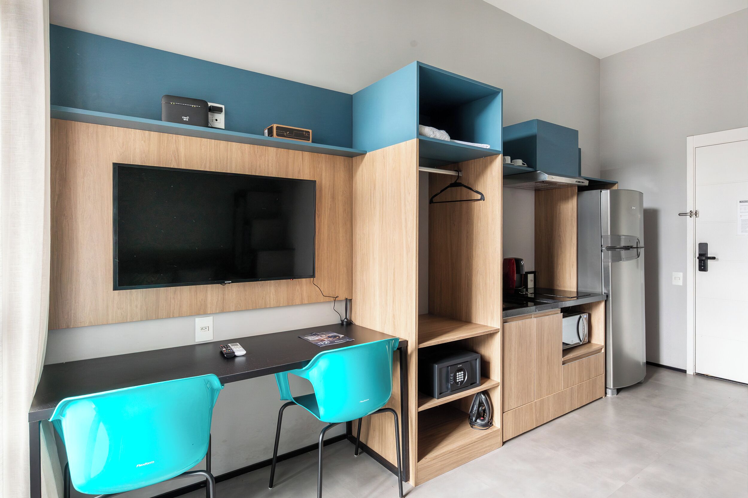 Een compacte kitchenette met een ingebouwde magnetron, een kleine koelkast en een koffiezetapparaat.