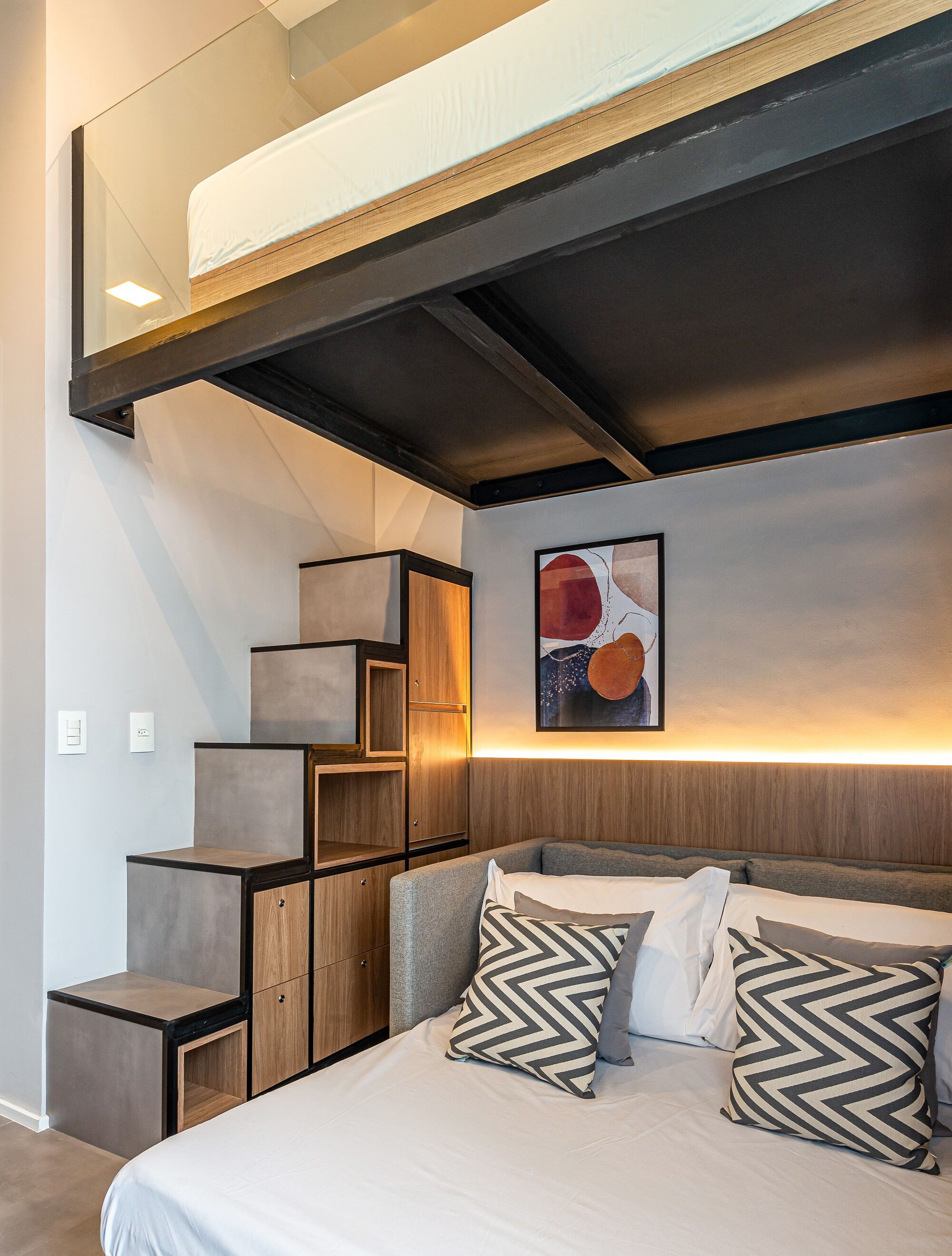 Une chambre moderne avec un lit superposé, des étagères intégrées et une œuvre d’art accrochée au mur.