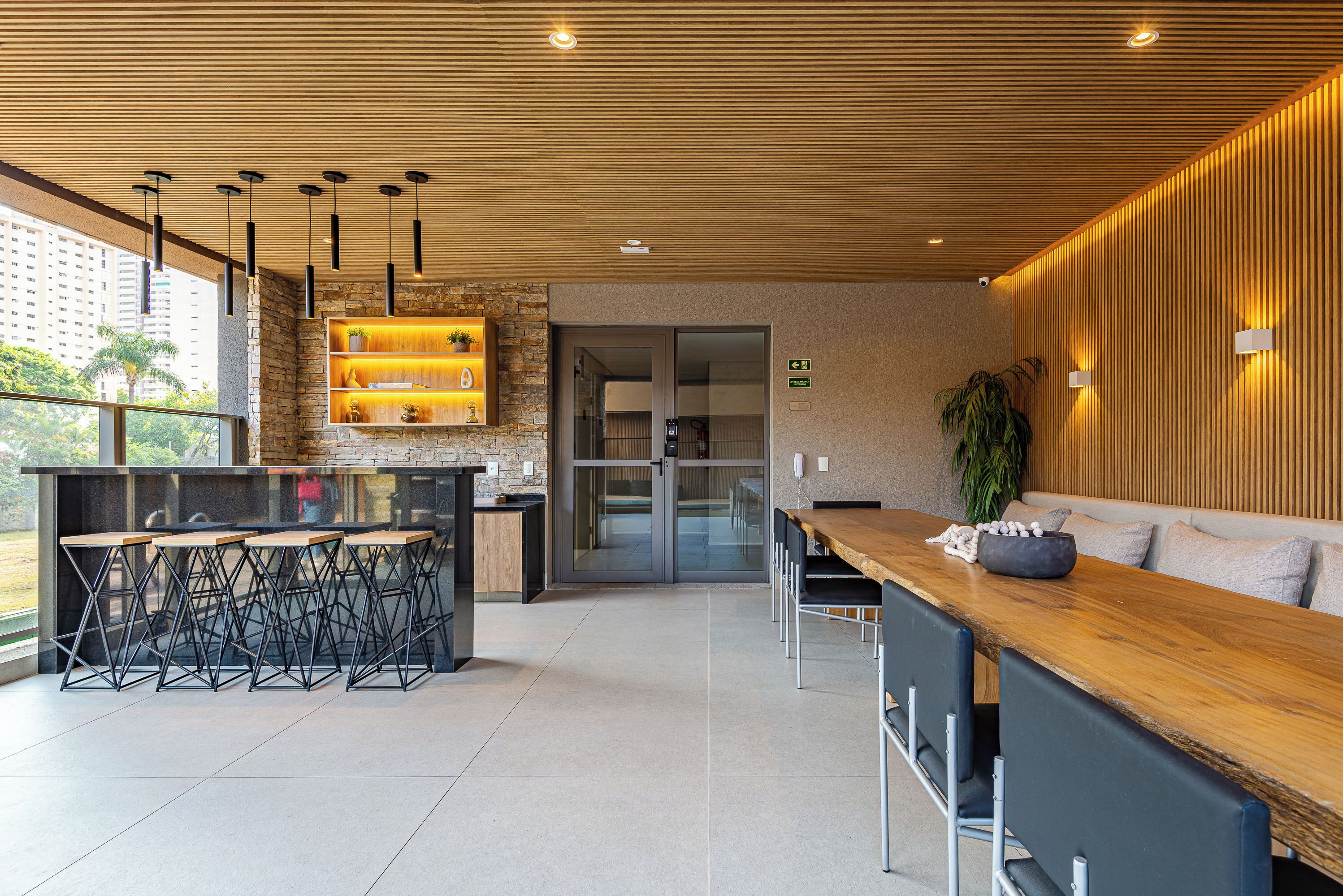 A modern kitchen area with a wooden countertop, black chairs, and a bar area.