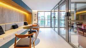Ein modernes Interieur mit einer Sitzecke, Tischen und einer Glastür, die nach draußen führt.