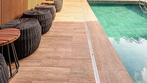 Ein Poolbereich auf dem Dach mit Holzboden, Liegestühlen und einem großen Pflanzgefäß.