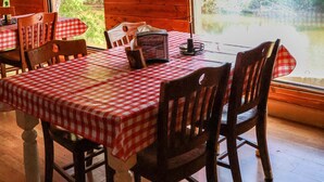 A dining area with checkered tablecloths, wooden chairs, and a view of a lake.