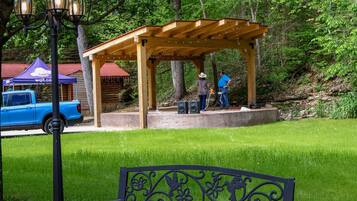 A park with a wooden gazebo, a bench, and a blue car parked nearby.