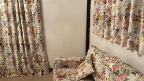 A room with a floral-patterned sofa and matching curtains.