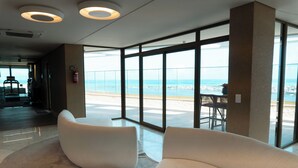 A modern interior with large windows, a seating area, and a view of the beach. - Roomo Transamerica Recife Parque do Cais (Recife)
