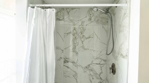 Shower area with a wall-mounted showerhead and a curtain for added privacy.