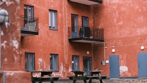 Un immeuble à plusieurs étages doté de balcons, de tables extérieures et d’une porte bleue.
