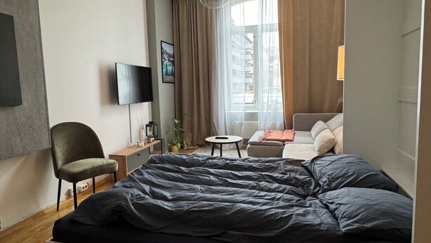 Une chambre d’hôtel moderne avec un grand lit, une télévision, une petite table et un canapé.