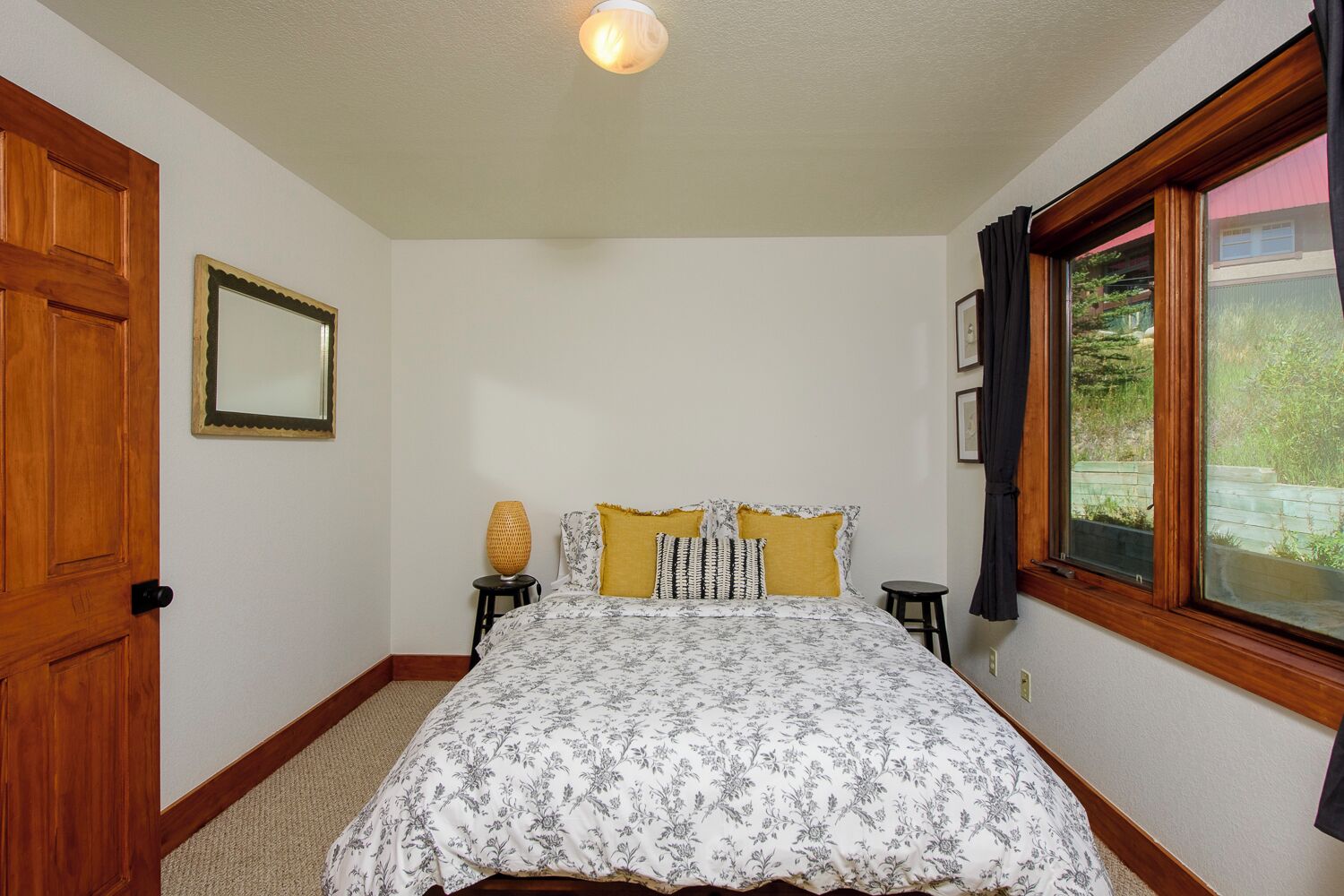 A bedroom with a bed, a window, a door, and a mirror.