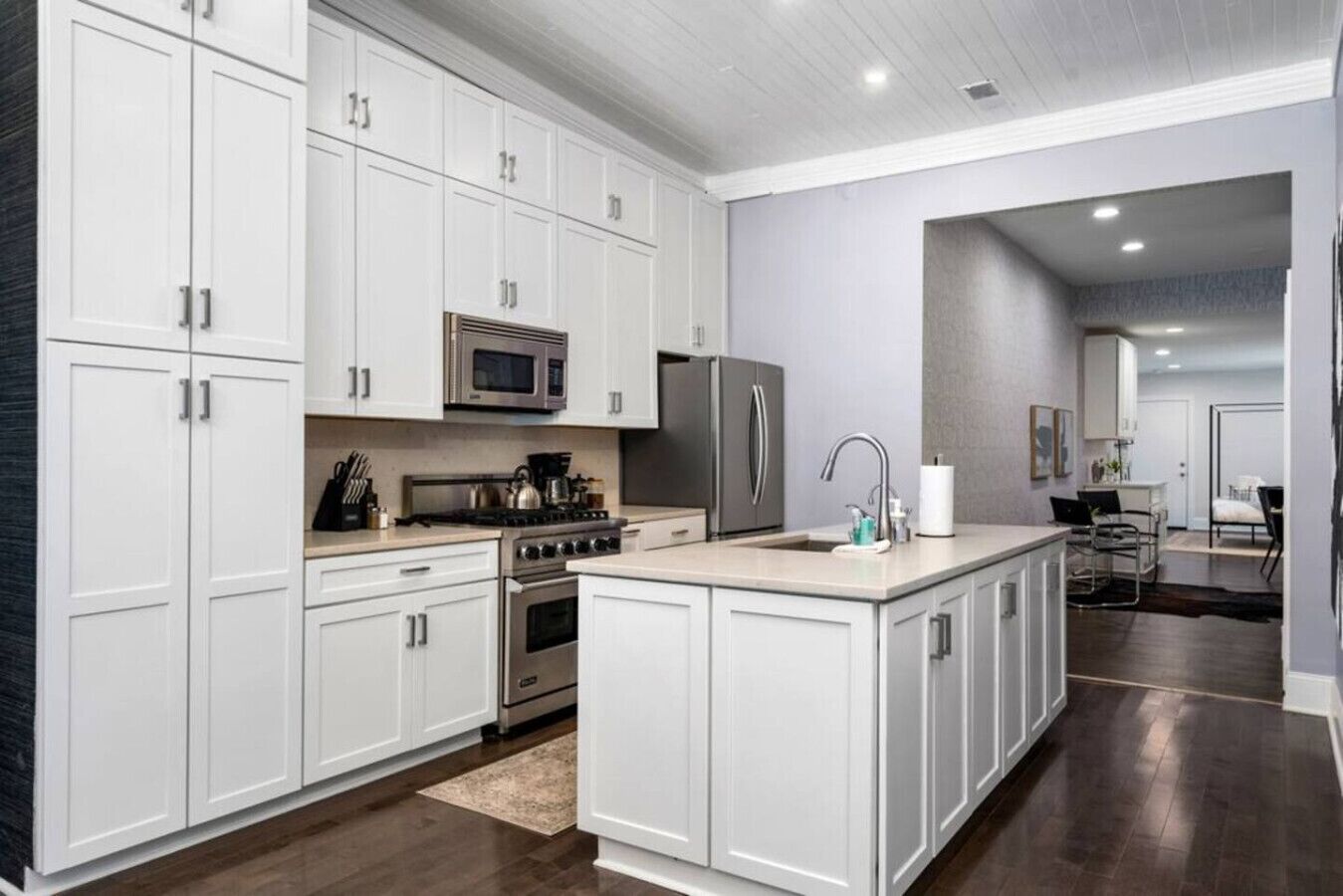 A modern kitchen with white cabinetry, stainless steel appliances, and a central island with a sink.