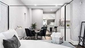 A modern hotel room with a large bed, a dining area, and a kitchenette. - Luxe Studio w/ King Bed + Sofa | Walk to OSU/Bars (Columbus)